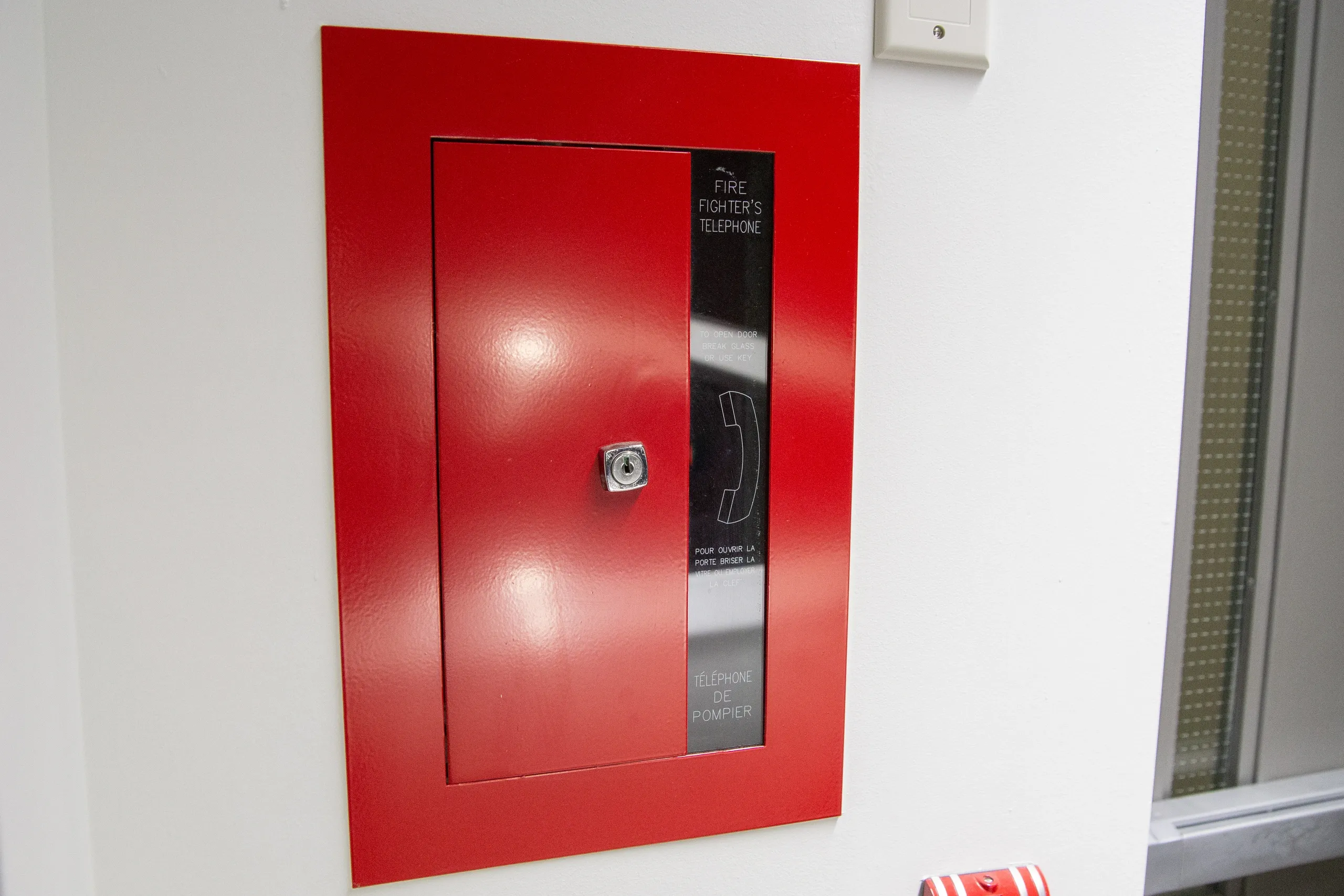 67db32ea2790b_Fire-Panel A red door with a glass window on the outside.